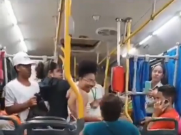 No vídeo, a mulher aparece ajoelhada no corredor do ônibus, já fora de sua cadeira de rodas. Ela se aproxima de outra passageira e, em questão de segundos, ambas começam a trocar agressões físicas, enquanto os outros passageiros assistem à cena sem intervir de imediato. (Foto: Reprodução/Redes Sociais)