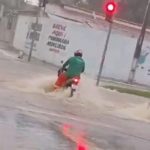 O rapaz não conseguiu segurar a força da água e perdeu o equilíbrio da motocicleta. (Foto: Reprodução)