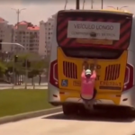 Ele se agarra em um ponto em que não pode ser visto pelo motorista, que segue conduzindo o ônibus com velocidade na pista seletiva. (Foto: Reprodução/Redes Sociais)